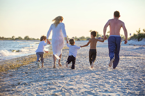 Happy young family running on beach before sunset
